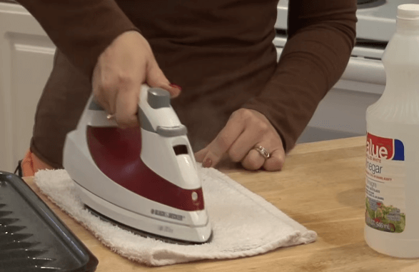 Rub the iron on the towel wet with a mixture of vinegar and baking soda.